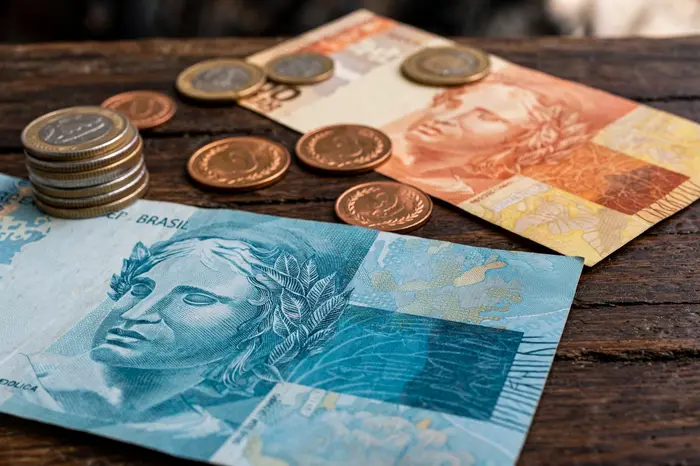 Cédulas e moedas de real sobre a mesa — calculadora ipca mostra o poder de compra